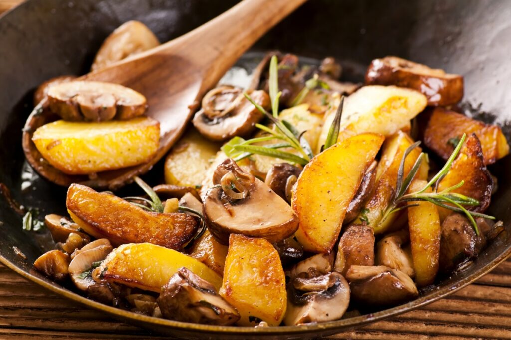 Cartofi cu ciuperci și ceapă la tigaie și o lingură de lemn