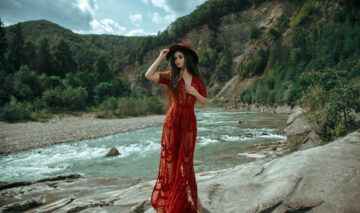 Fată frumoasă îmbrăcată într-o rochie roșie stă într-o pădure