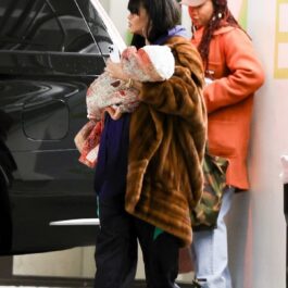 Rihanna cu o haină de blană într-o parcare în timp ce își ține băiețelul în brațe