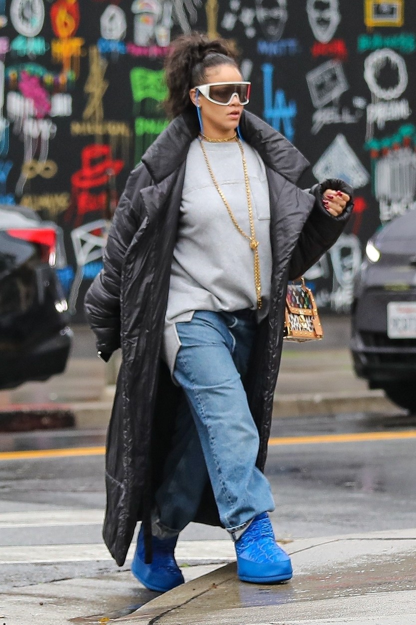 Rihanna, cu un pardesiu negru, un hanorac și i pereche de jeanși largi