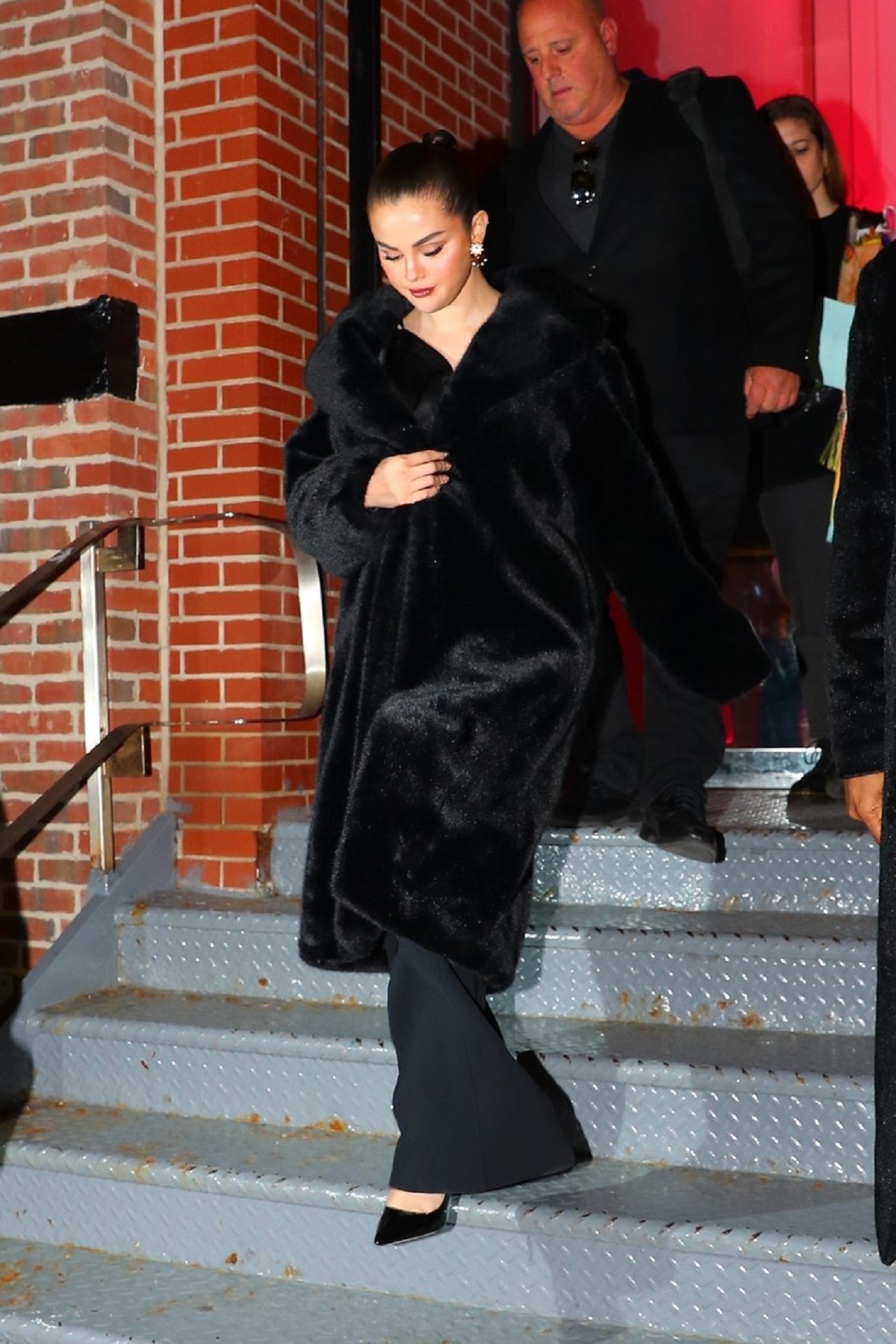Selena Gomez în timp ce coboară scările și poartă o haină de blană neagră