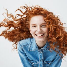 O femeie frumoasă cu părul creț roșcat pentru a ilustra cum să ai grijp de acest tip de păr