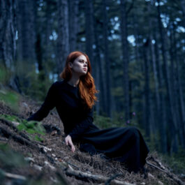Fată frumoasă îmbrăcată în negru stă într-o pădure
