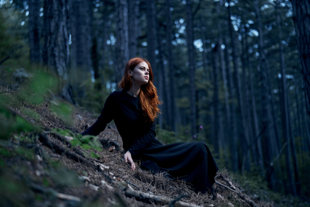 Fată frumoasă îmbrăcată în negru stă într-o pădure