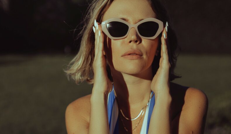 O femeie care poartă ochelari de soare, vara, într-o rochie cu decolteu