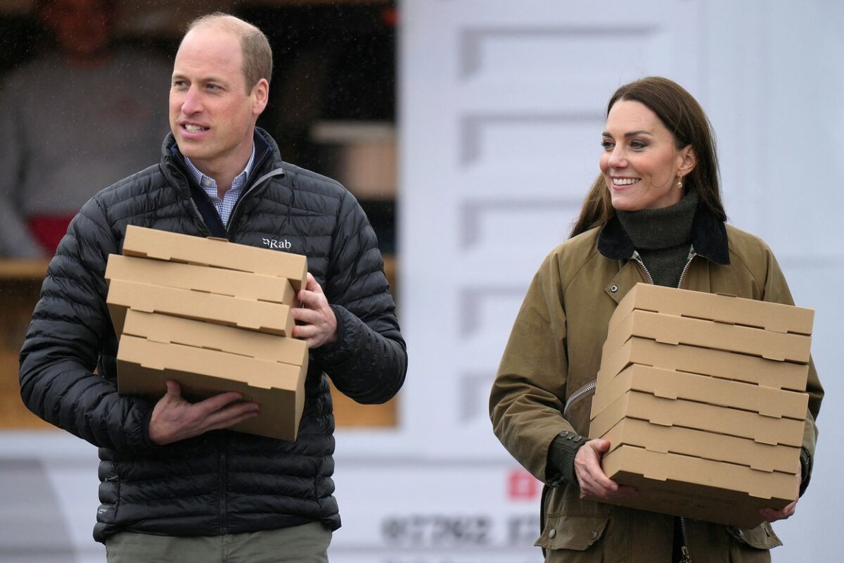 Prințul și Prințesa de Wales cu mai multe cutii de pizza în brațe