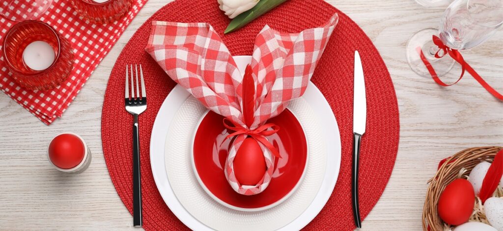 O masă pe care se află un șervet roșu, o farfurie și un ouă de paște cu urechi de iepuraș