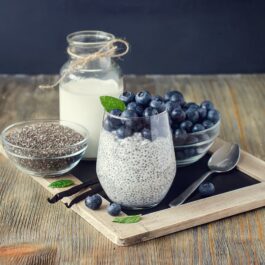 Un pahar cu lapte vegetal, afine și semințe de chia pentru a ilustra faptul că beneficiile semințelor de chia pot fi inluențate de modul în care acestea sunt consumate