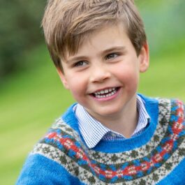 Prințul Louis, într-un pulover albastru, cu cămașă, în timp ce zâmbește