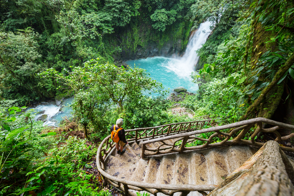 Un bărbat care coboară mai multe trepte spre o cascadă din Costa Rica