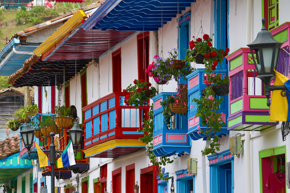Imagine cu o stradă din Columbia, cu case colorate, cu flori la geam
