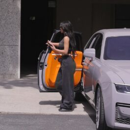 Kim Kardashian, într-o mașină gri, cu interior portocaliu, într-o ținută neagră