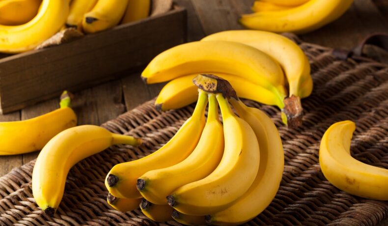 Un coș împletit pe care se află mai multe banane coapte