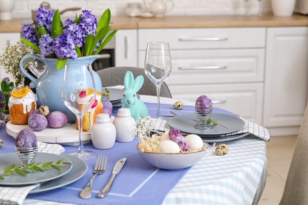 Masa de Paște aranjată cu obiece de decorat în nuanțe de violet și albastru