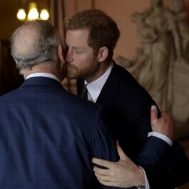 Regele Charles în timp ce se sărută pe obraz cu fiul său, Prințul Harry