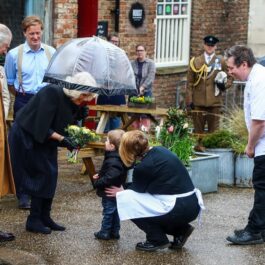 Regina Camilla în timp ce primește un buchet de flori de la un băiețel