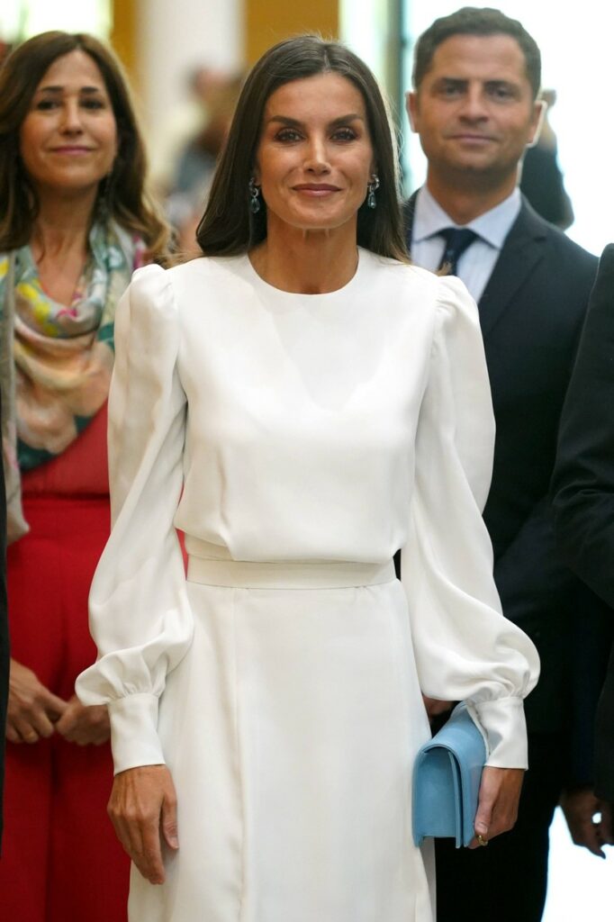Regina Letizia, într-o rochie albă, la un eveniment, cu un clutch albastru în mână