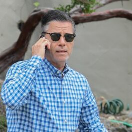 Scriitorul J.R Moehringer, fotografiat în timp ce vorbește la telefon și e îmbrăcat într-o cămașă albastră și poartă ochelari de soare