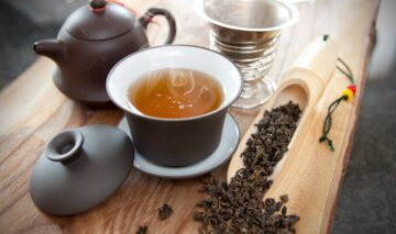 Ceaiul Oolong srvit într-o ceașcă neagră alături de un ceainic