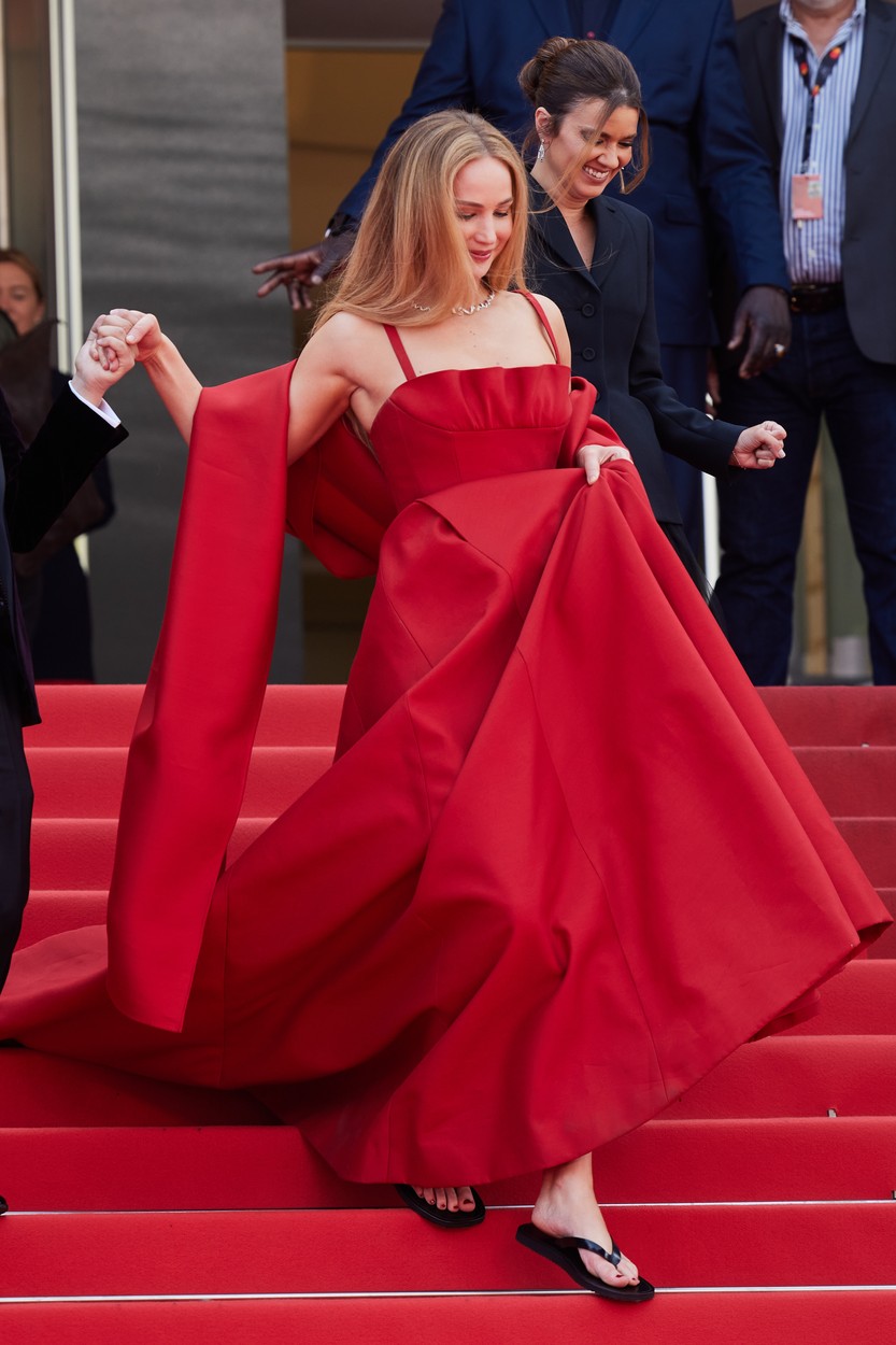 Jennifer Lawrence, într-o rochie roșie, fotografiată în timp ce coboară treptele pe covorul roșu la Cannes 2023
