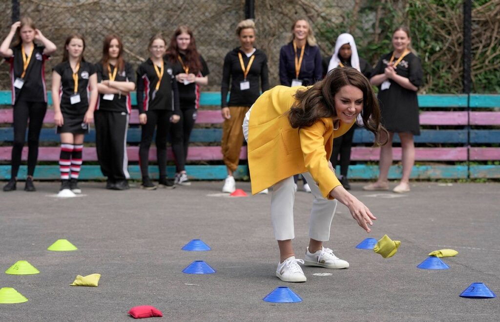 Kate Middleton pe un teren de sport în timp ce face activități fizice cu un grup de elevi