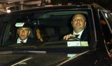 Doi șoferi care conduc mașina în care se pot observa Meghan Markle și Prințul Harry