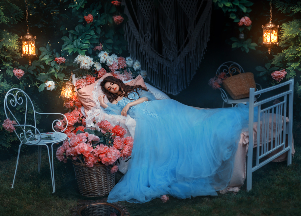 O zână îmbrăcată într-o rochie cu tul care doarme într-un pat în pădure