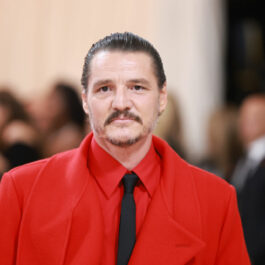 Pedro Pascal, într-un costum roșu, cu o cravată neagră, la Met Gala 2023