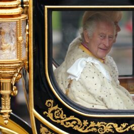 Regele Charles privește fanii prin geamul caleștii de aur