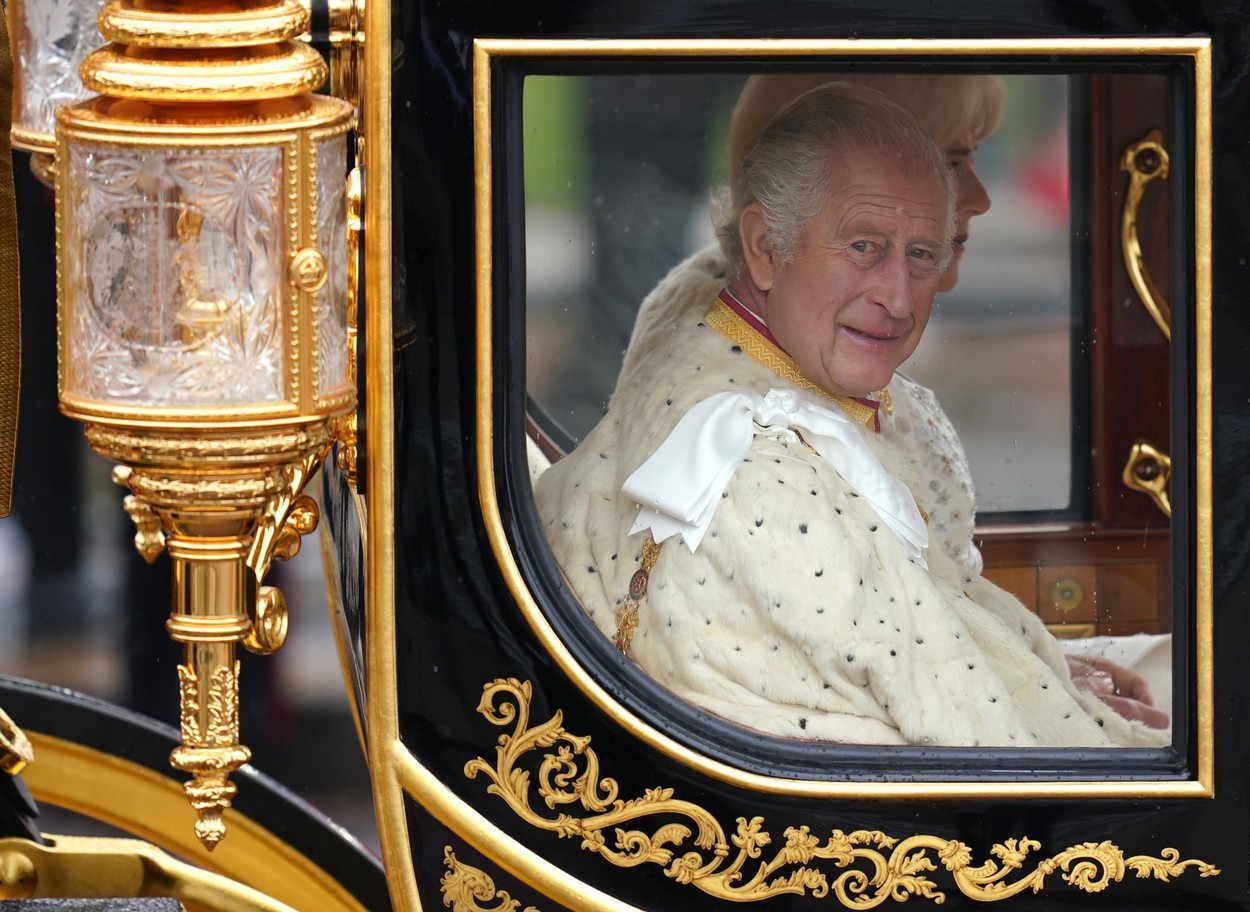 Regele Charles privește fanii prin geamul caleștii de aur