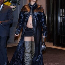 Rihanna într-un palton negru din piele, o fustă scurtă și o pereche de cizme peste genunchi