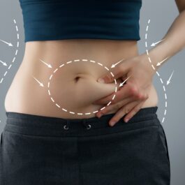 O femeie care își ciupește abdomenul pentru a ilustra câteva trucuri pentru a reduce grăsimea abdominală
