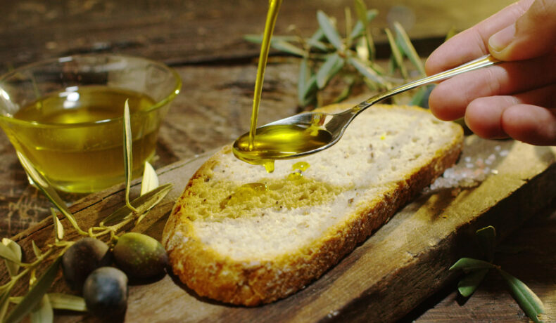 Ulei de măsline pus pe pâine cu ajutorul unei lingurițe