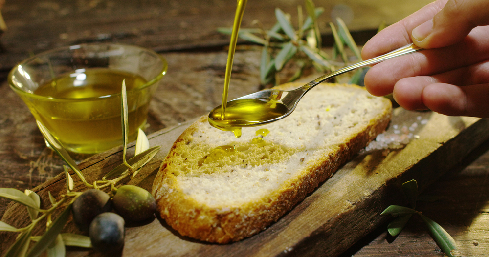 Ulei de măsline pus pe pâine cu ajutorul unei lingurițe