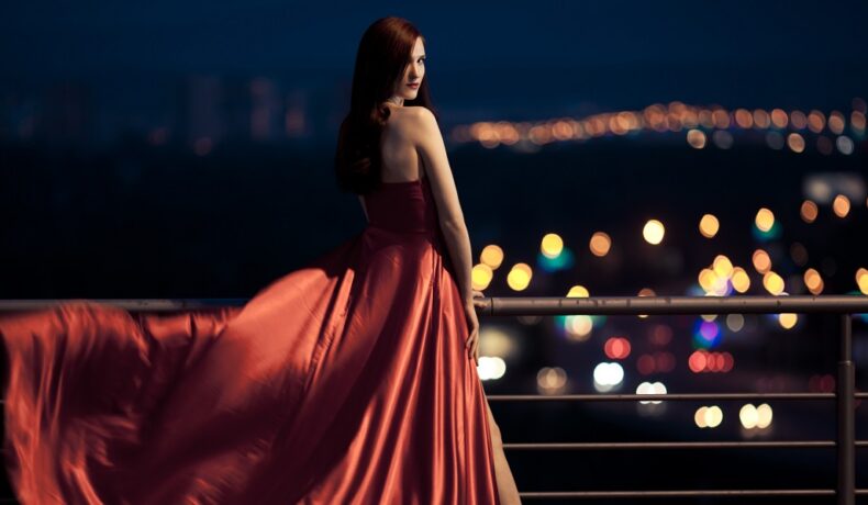 O femeie frumoasă, într-o rochie roșie, care privește înainte spre un nou capitol din viața sa