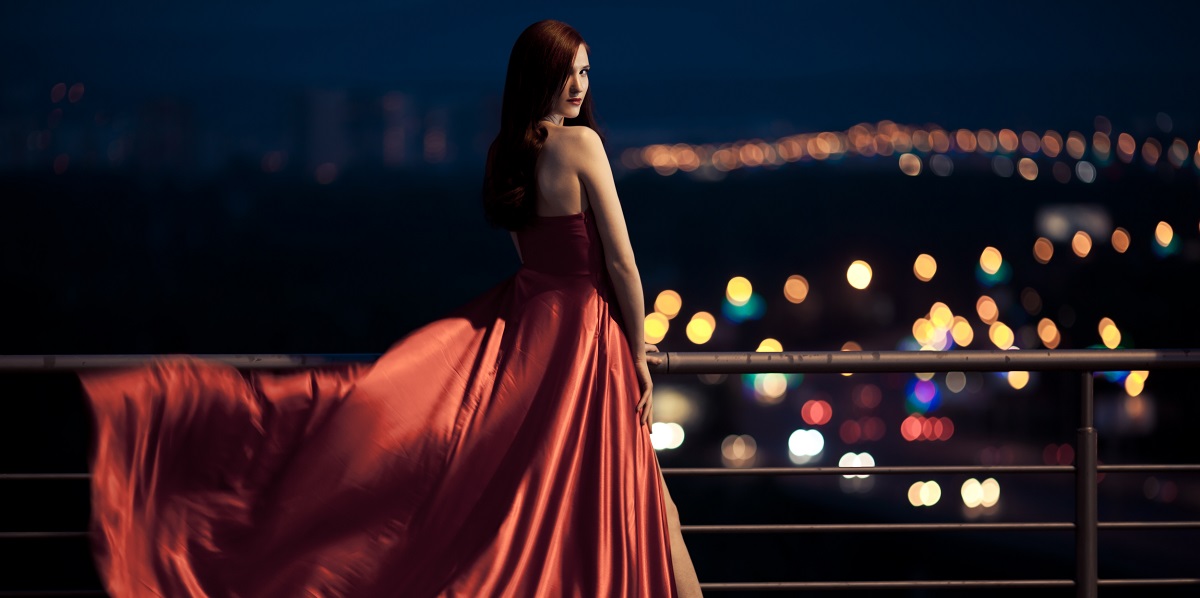 O femeie frumoasă, într-o rochie roșie, care privește înainte spre un nou capitol din viața sa