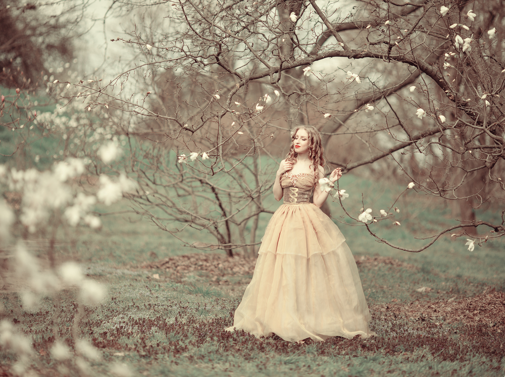 Fată frumoasă îmbrăcată într-o rochie lungă stă într-o pădure