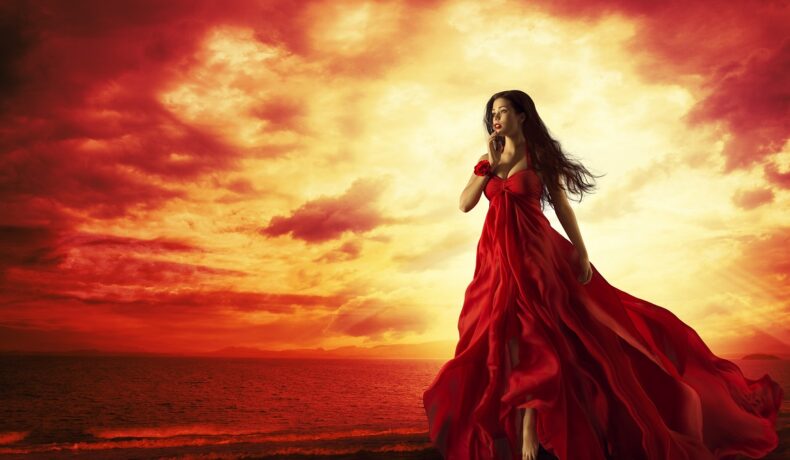O femeie frumoasă, într-o rochie roșie, care ilustrează una dintre cele trei zodii care pierd bani în luna iunie 2023