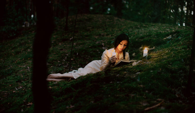 O femeie care stă la lumina lumânării și citește dintr-o carte