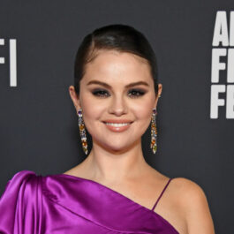 Selena Gomez, într-o rochie mov, machiată discret, cu o pereche de cercei lungi, colorați