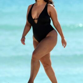 Ashley Graham în timp ce se plimbă pe plajă într-un costum de baie negru