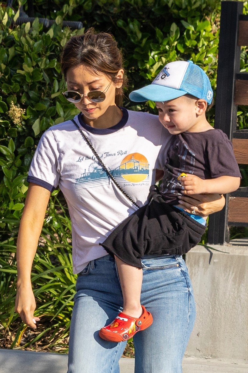 Brenda Song, într-un tricou și blugi, cu fiul ei cel mic în brațe