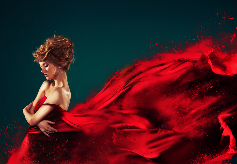 O femeie tânără, într-o rochie roșie și lungă, care se dizolvă în aer