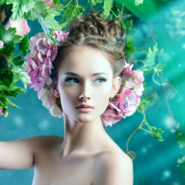 O femeie tânără cu flori prinse în păr care stă sub o iederă înflorită