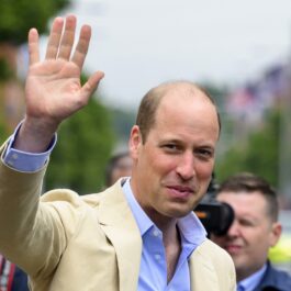 Prințul William într-un costum crem în timp ce face cu mâna mulțimii