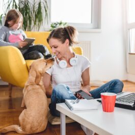 O femeie frumoasă care se relaxează alături de câinele și copilul ei după o zi stresantă de lucru