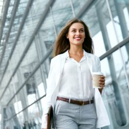 O femeie de succes cu o cafea în mână care merge la birou