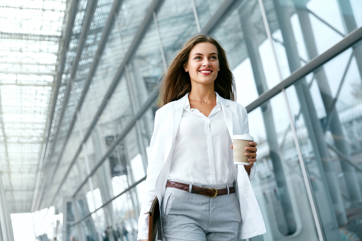 O femeie de succes cu o cafea în mână care merge la birou