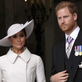 Meghan Markle într-un costum alb și Prințul Harry la un costum negru în timp ce participă la Ziua Recunoștinței în Londra în 2022