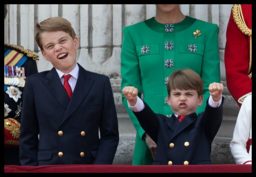 Prințul Louis cu mâinile în aer, în timp ce se distrează la balconul Palatului Buckingham